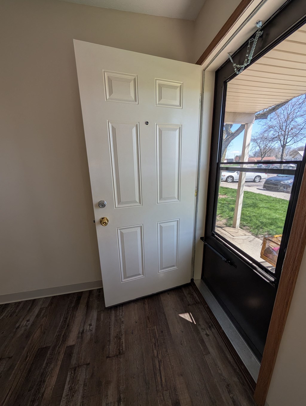 A white door with a gold handle is in a room with wood flooring.