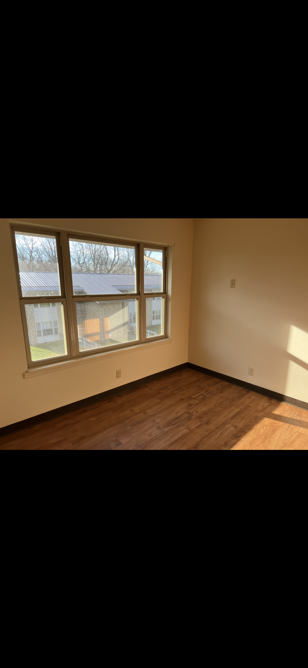 A room with a large window and wooden flooring.