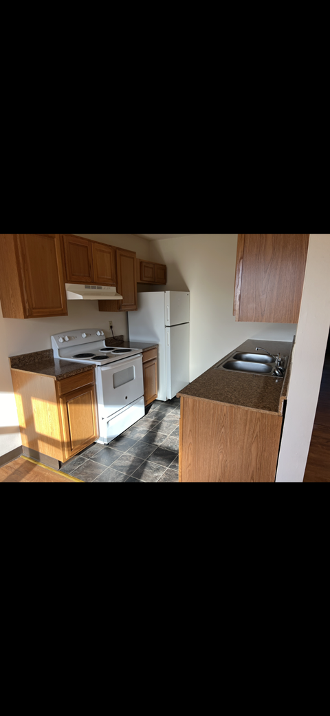 A kitchen with wooden cabinets and a white stove top oven.