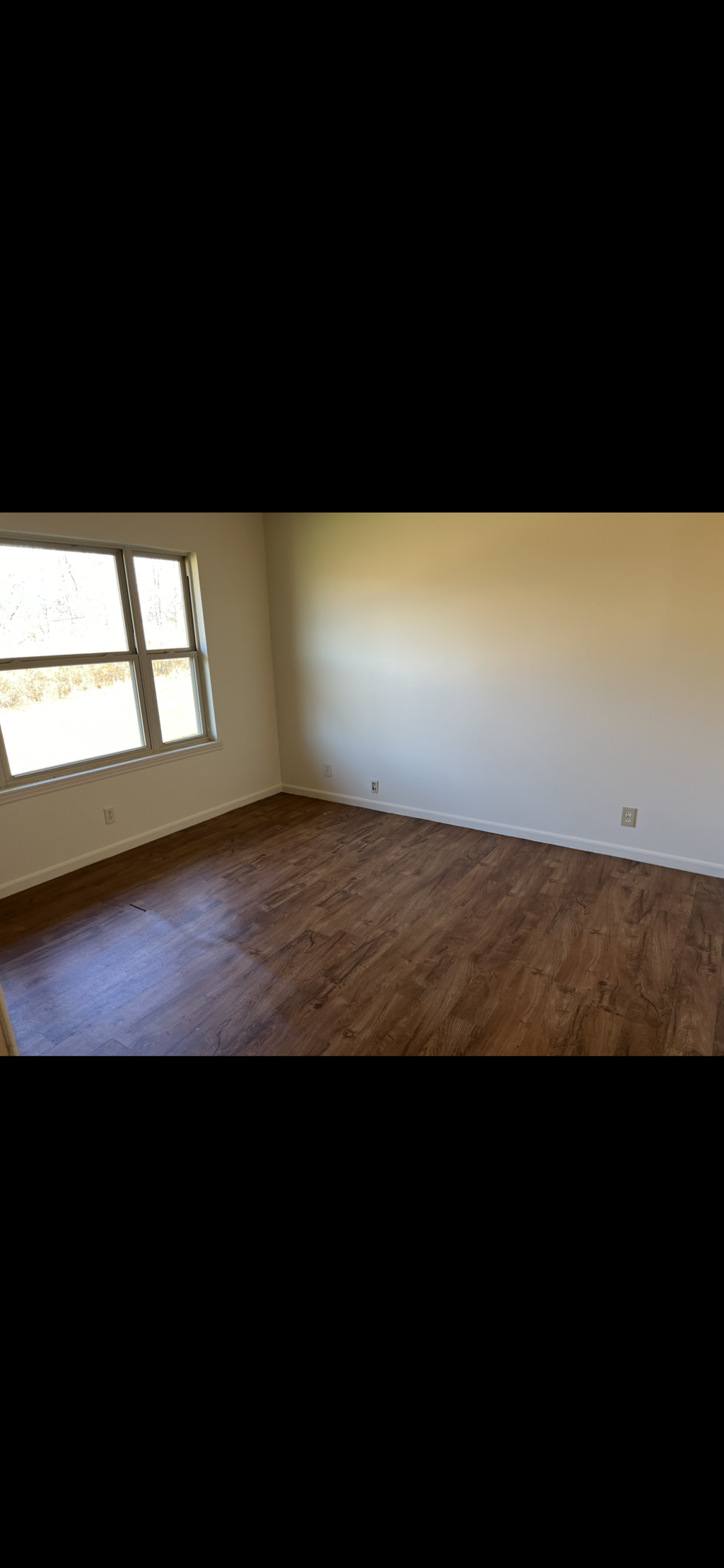 A room with wooden flooring and a window.