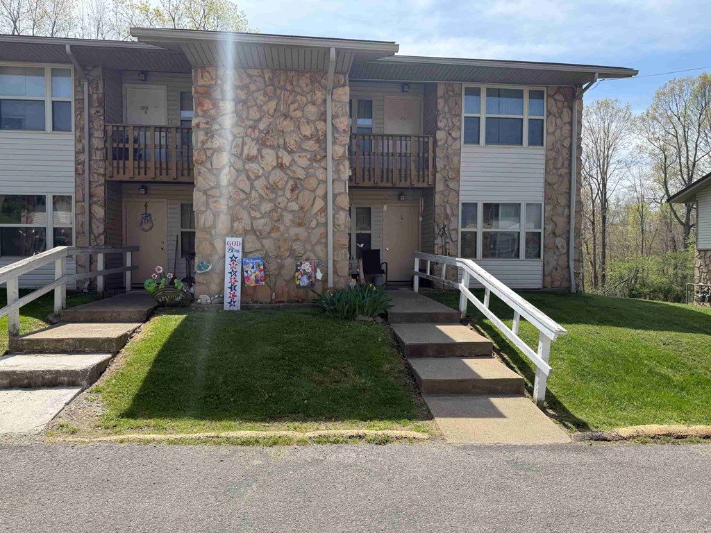 A sunny day at a stone building with a white fence and a small garden in front.