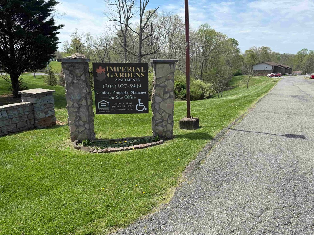 A sign for Imperial Gardens apartments stands in a grassy area.