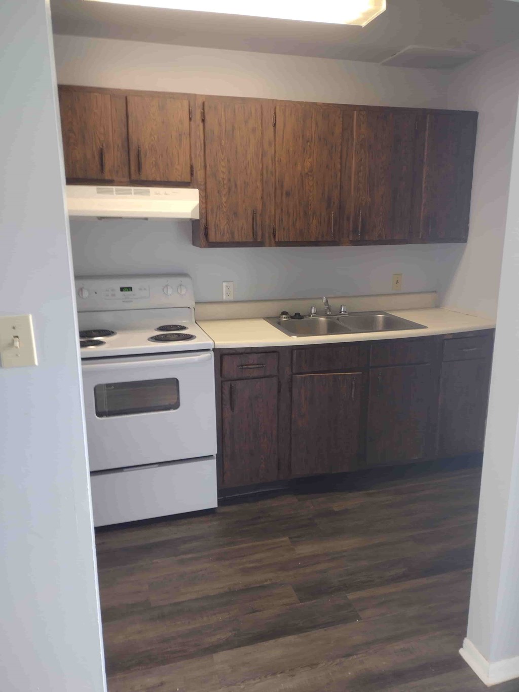 A kitchen with a white stove and wooden cabinets.