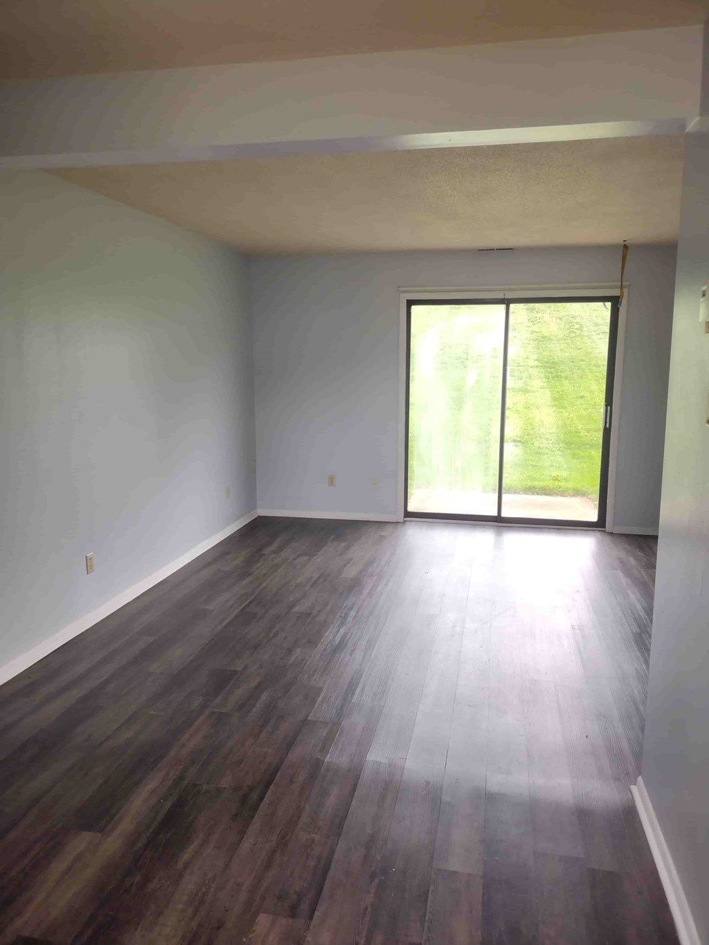 A room with wooden flooring and a sliding glass door.