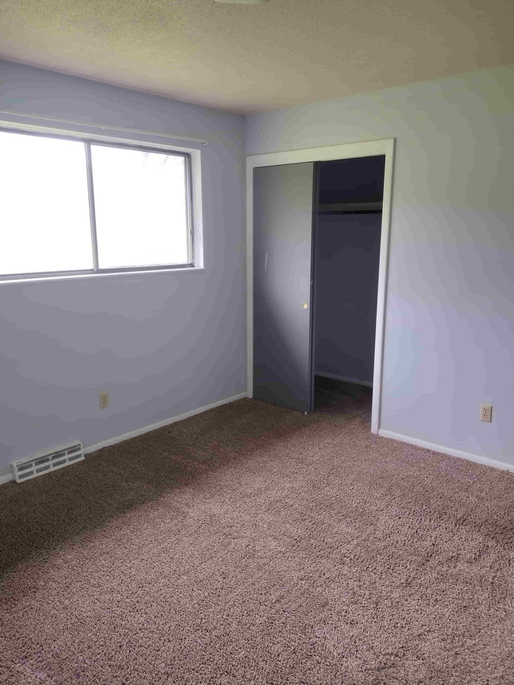 A room with a carpeted floor and a window.