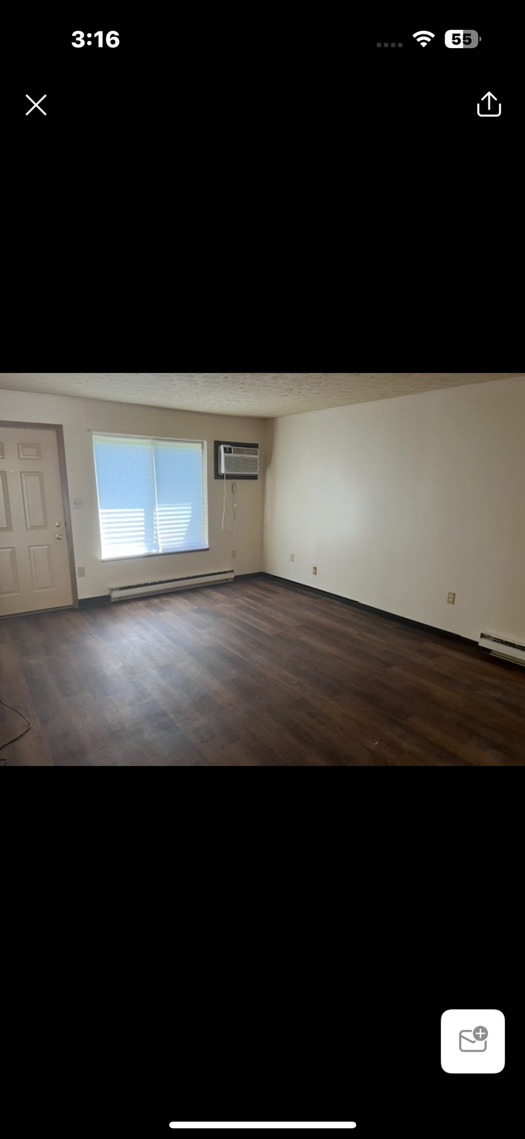 A room with wooden flooring and a window with blinds.