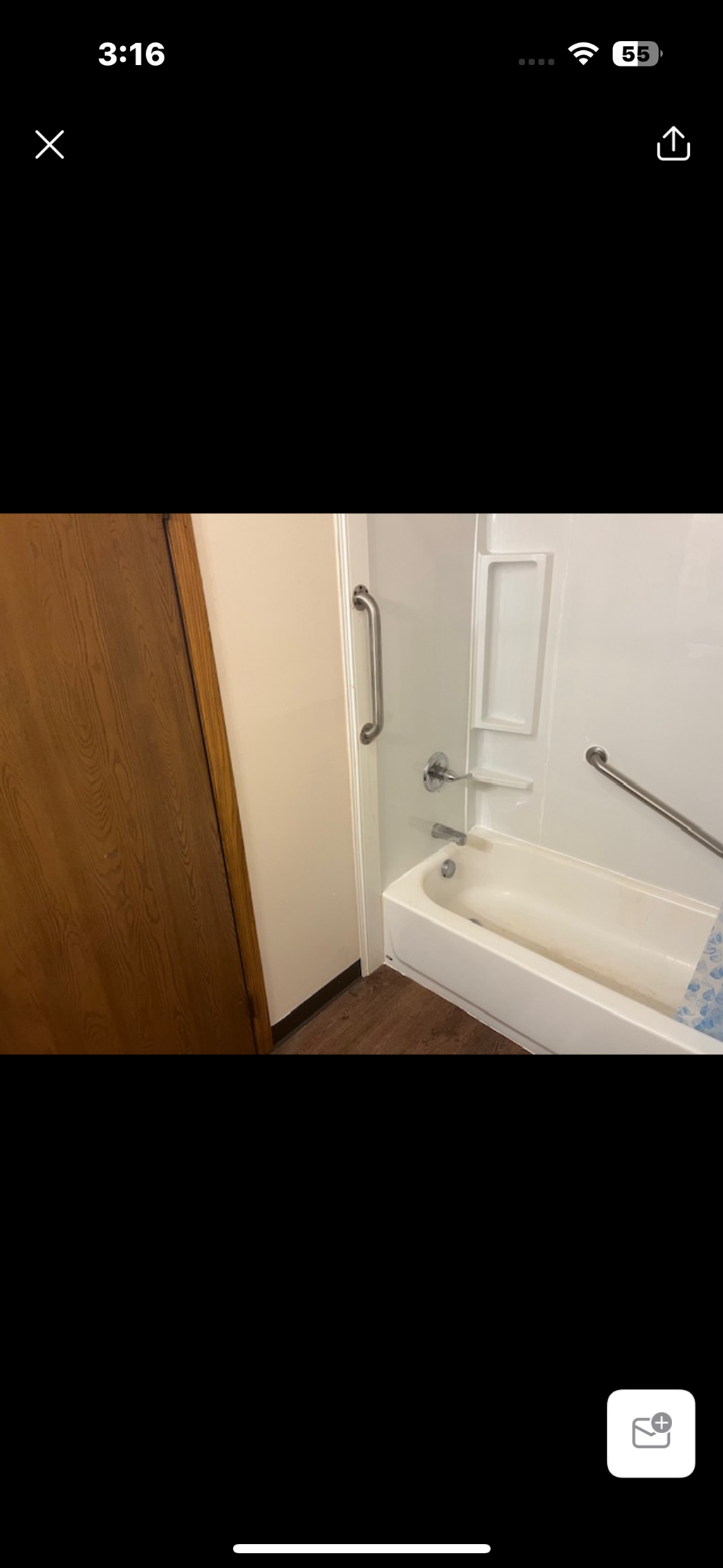 A white bathtub with a shower head and a wooden door.