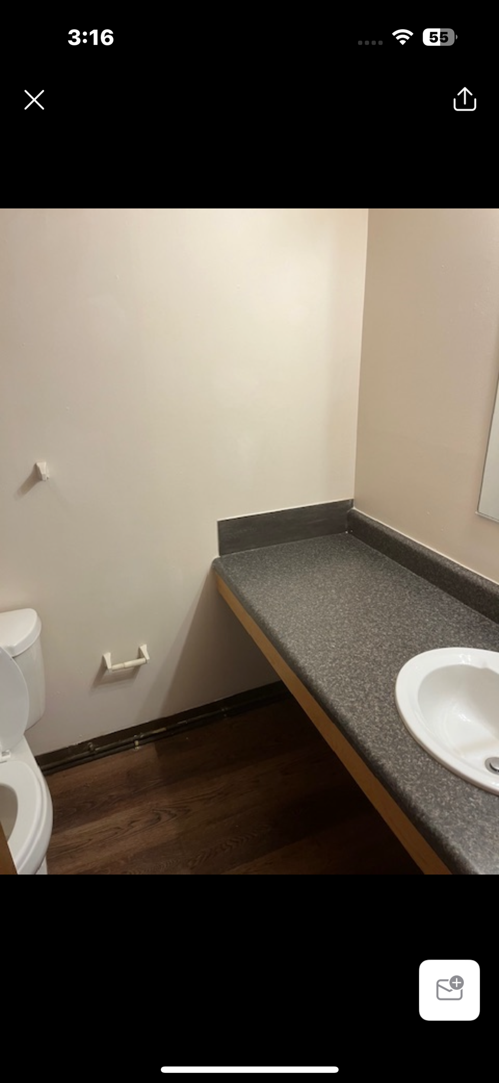 A bathroom with a toilet, sink, and mirror.