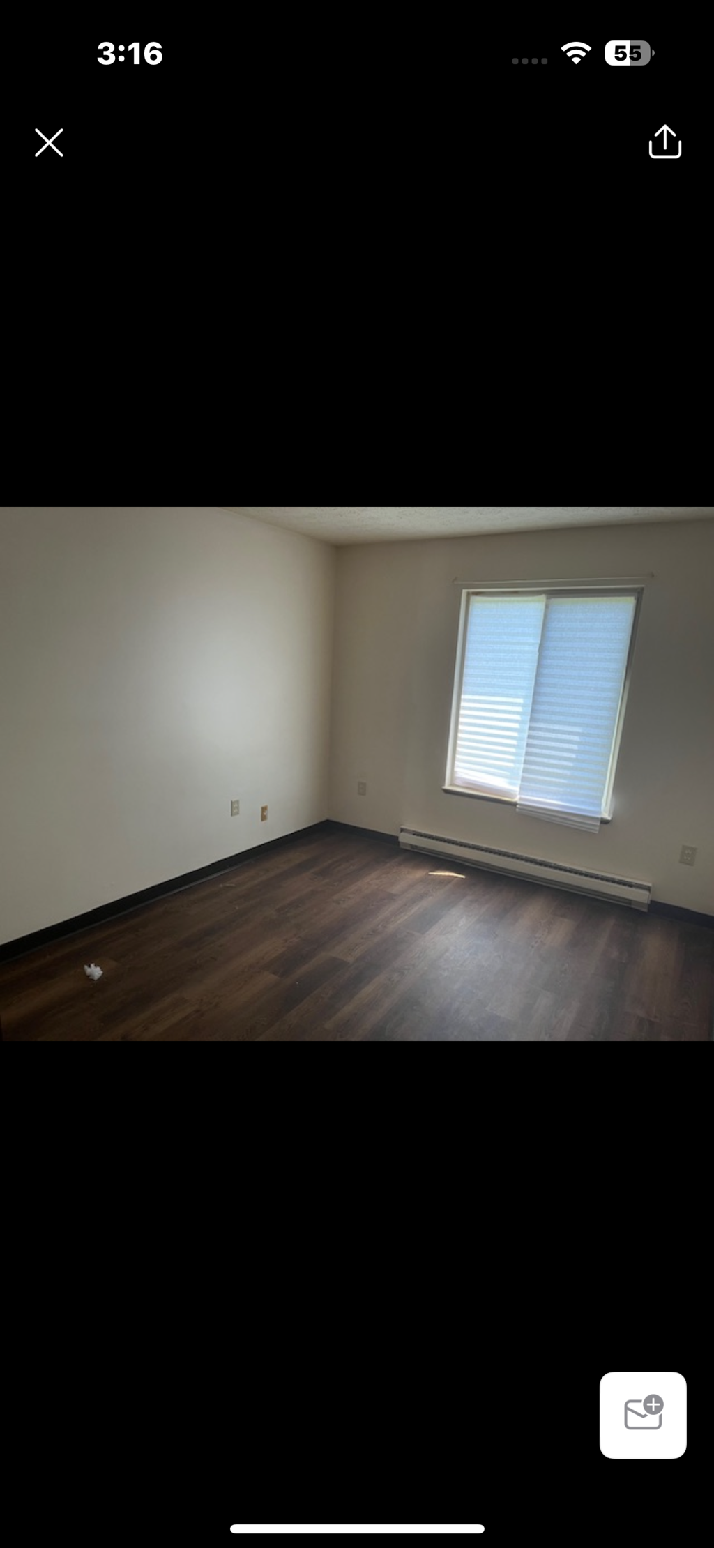A room with wooden flooring and a window with blinds.