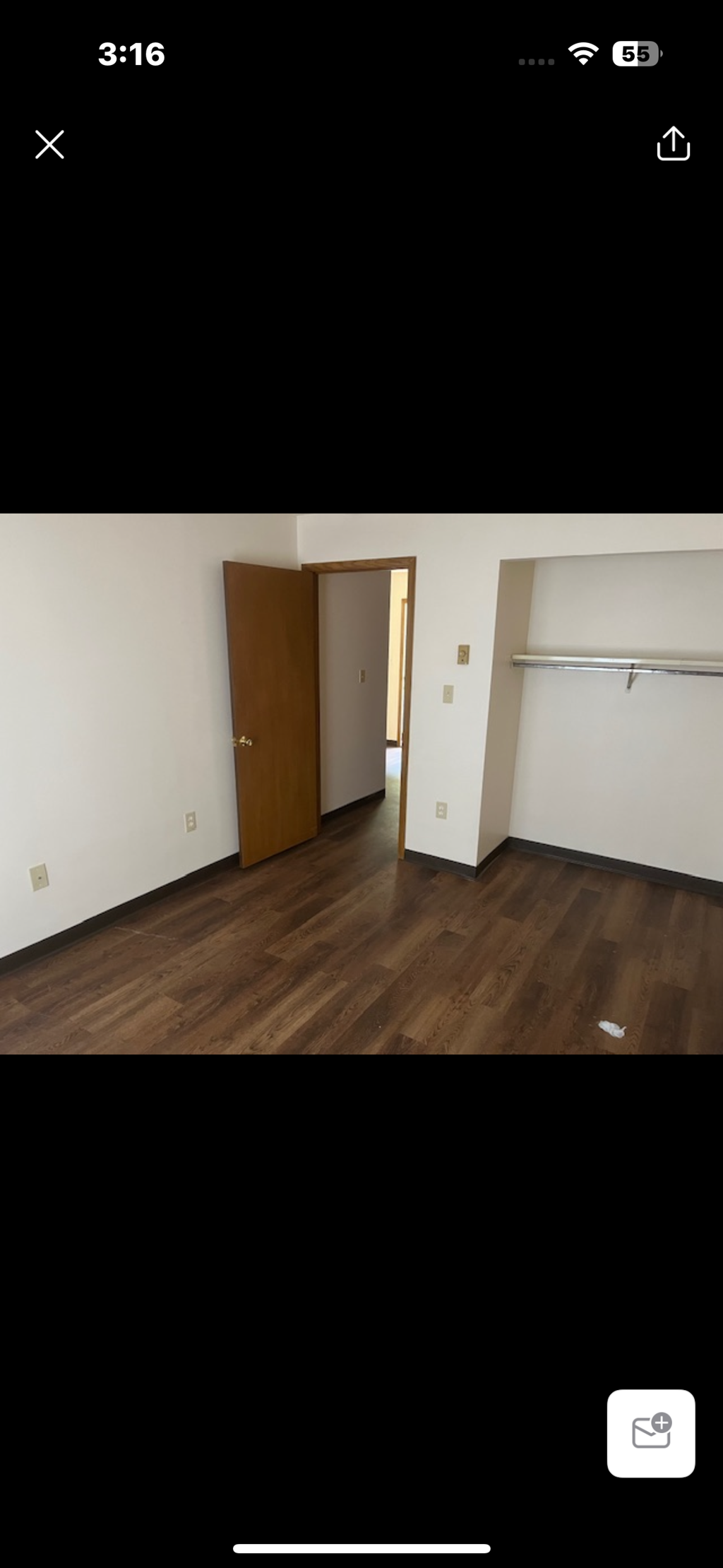 A room with wooden flooring and a brown door.