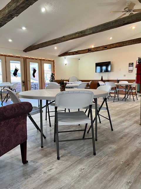A room with a white table and chairs and a ceiling fan.
