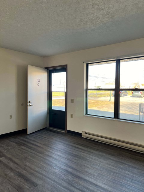 A room with a door and a window overlooking a parking lot.