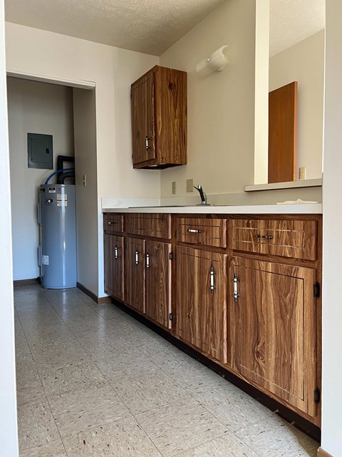 A kitchen with wooden cabinets and a white counter.