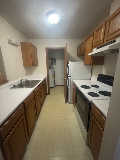 A kitchen with white appliances and brown cabinets.