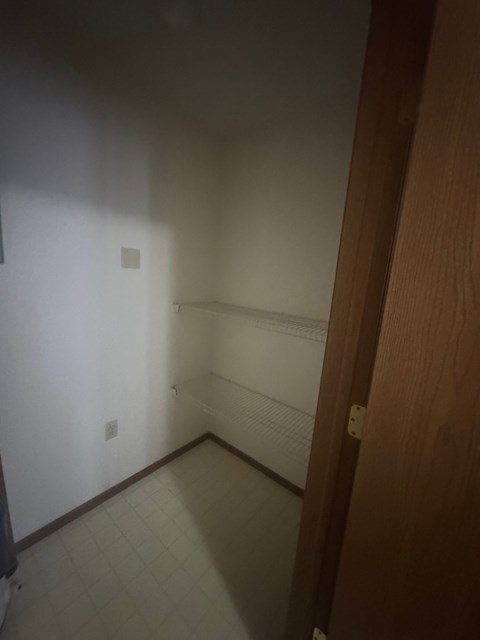 A hallway with a white wall and a brown door.