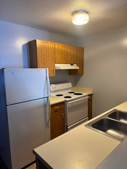 A small kitchen with a refrigerator, stove, and sink.