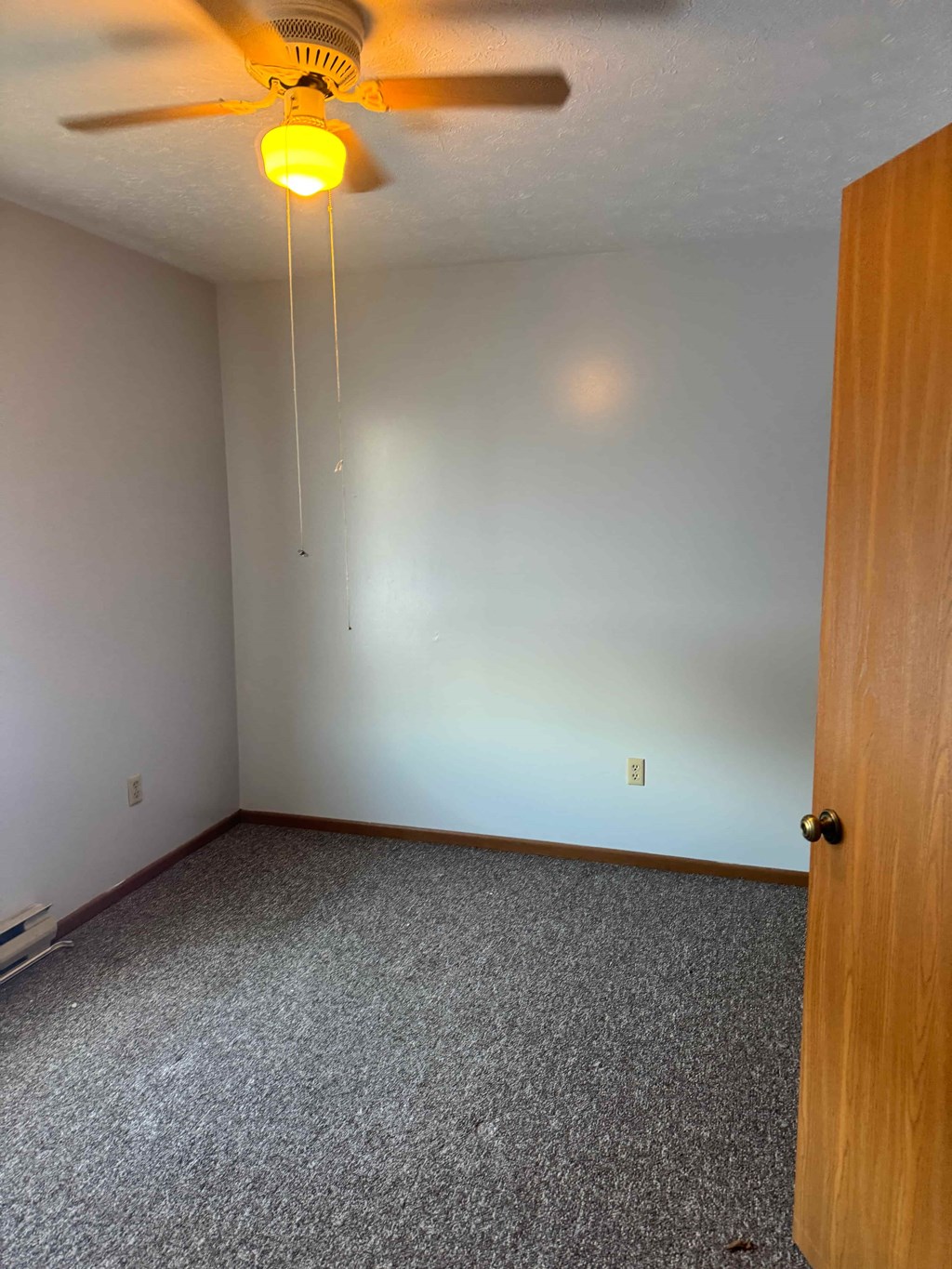 A room with a ceiling fan and a door.