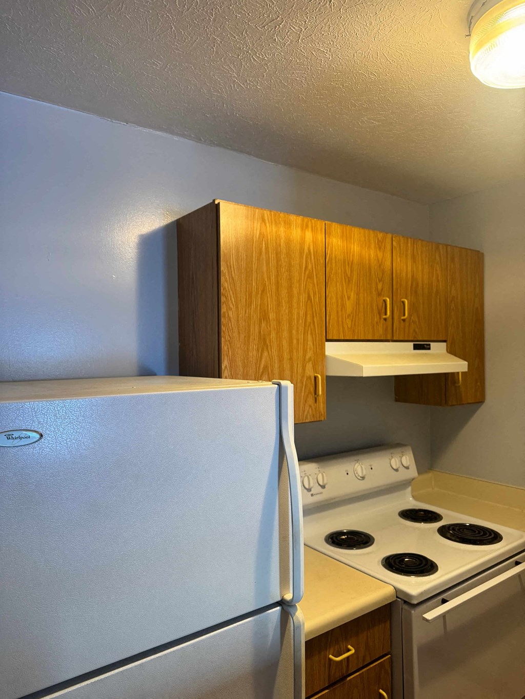 A white refrigerator is in a kitchen next to a stove.