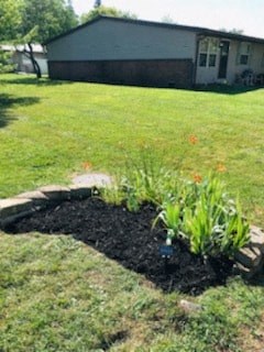 A flower bed in the middle of a grassy area.