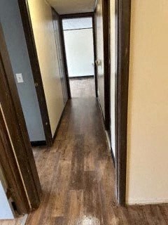 A long hallway with wood floors and a white door at the end.