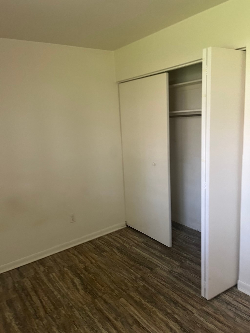 A room with a white door and a brown floor.