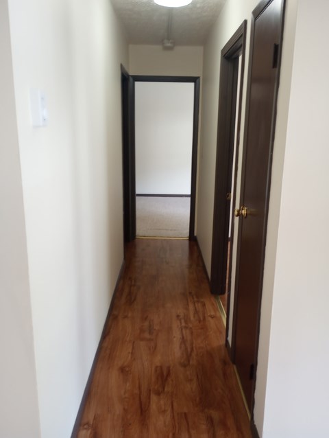 A long hallway with a brown floor and white walls.