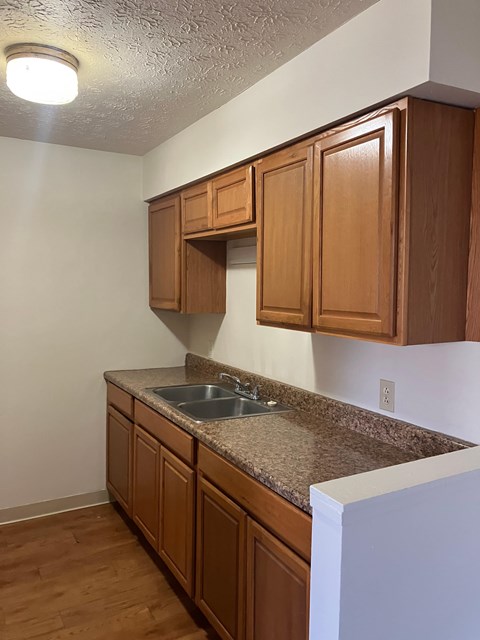 A kitchen with brown cabinets and a granite countertop.