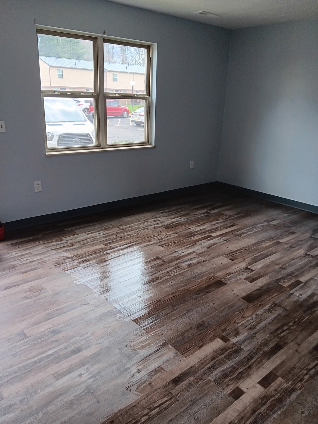 A room with wooden flooring and a window.