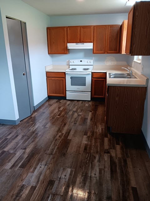 A kitchen with wooden floors and white appliances.