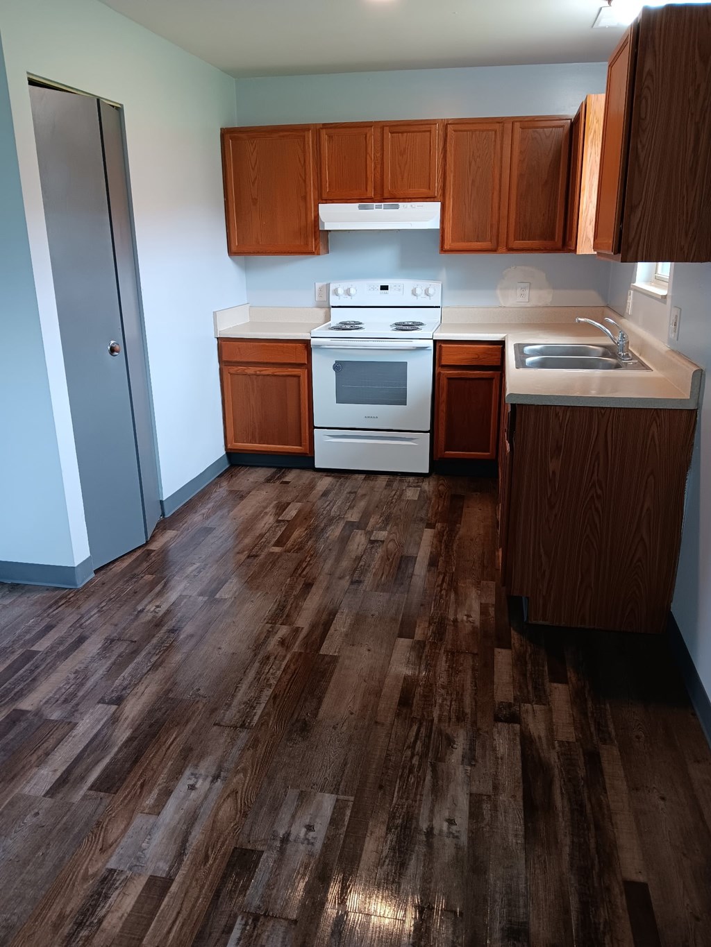 A kitchen with wooden floors and white appliances.