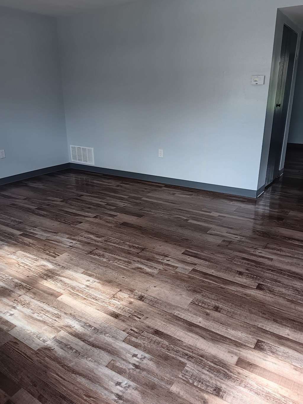 A room with wooden flooring and a door on the right.