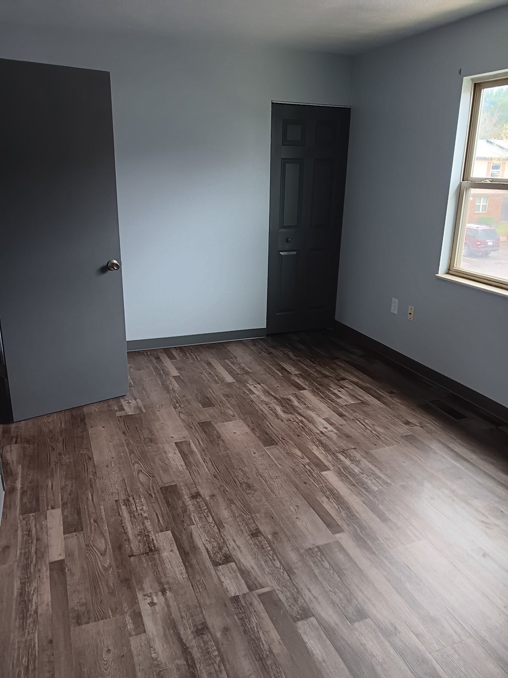 A room with a dark wood floor and a black door.