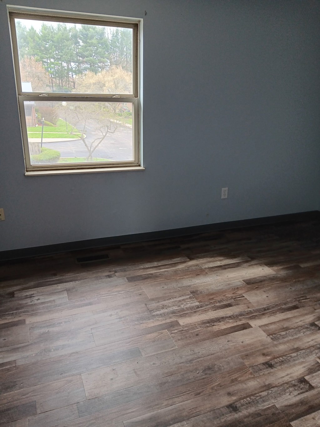 A room with a window and wooden flooring.