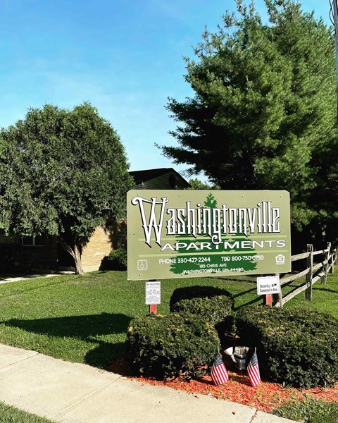 A sign for Washingtonville Apartments is displayed in front of a building.
