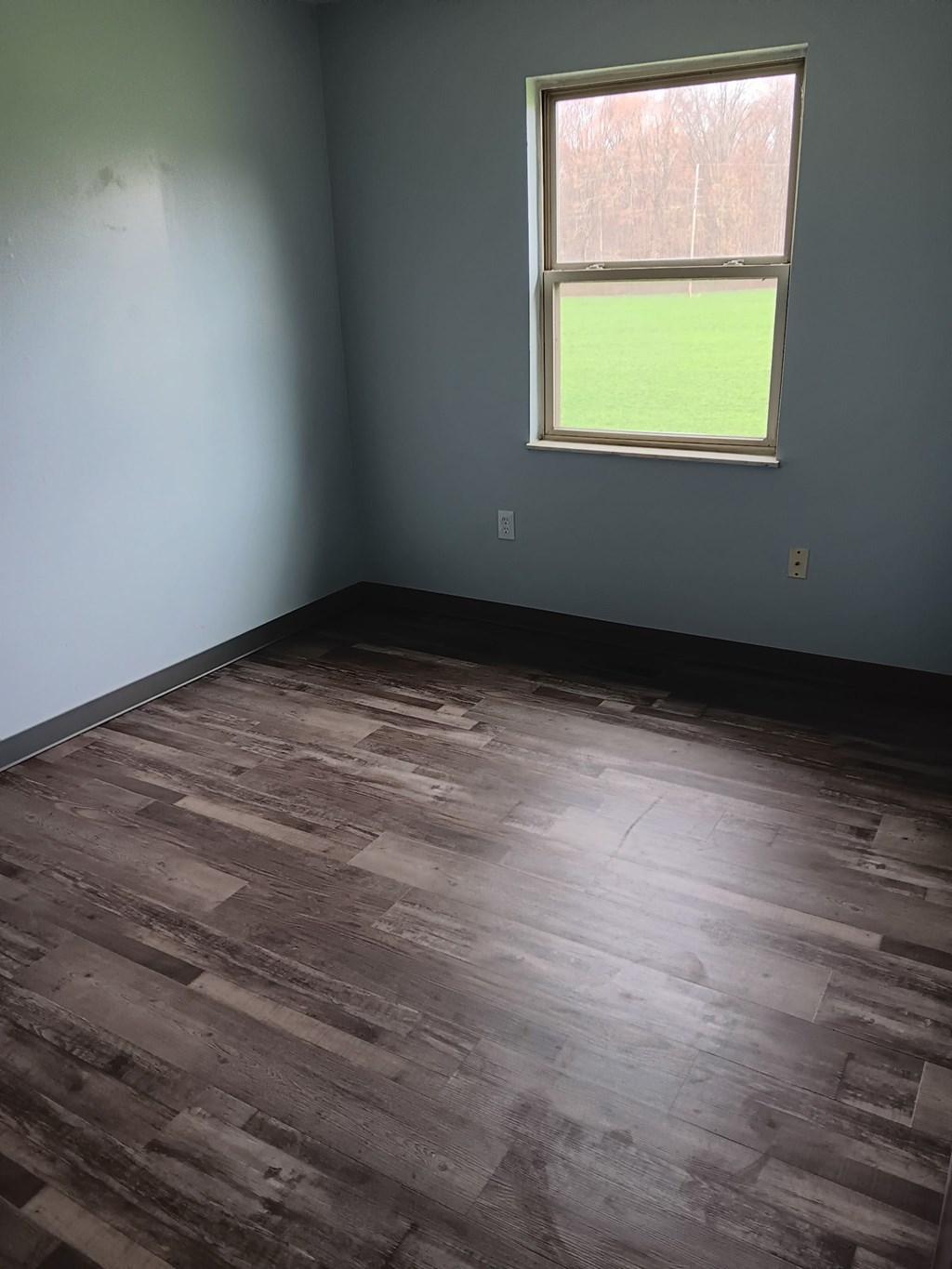 A room with a window and wooden flooring.
