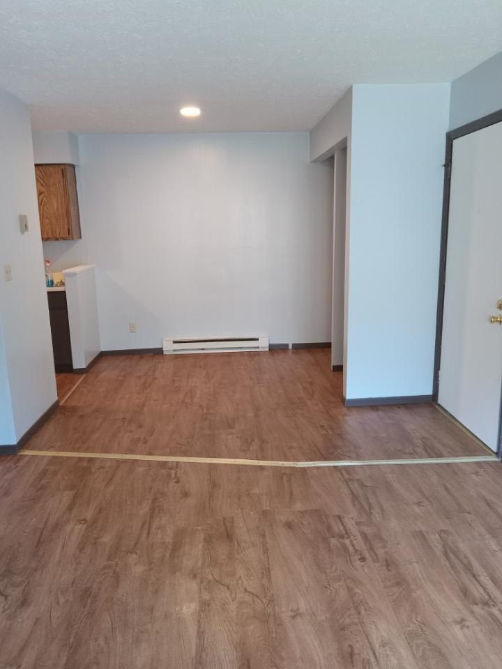 A room with wooden flooring and a white wall.