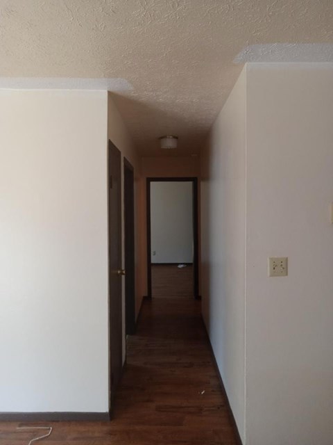 A long, narrow hallway with a door at the end.