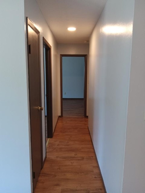 A long hallway with a brown door on the left and a blue door on the right.