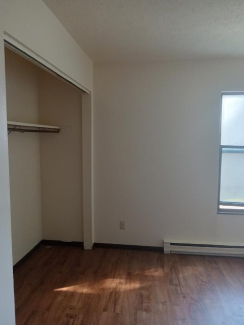 A room with a window and a wooden floor.