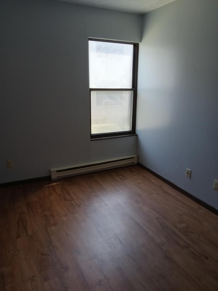 A room with a window and a wooden floor.