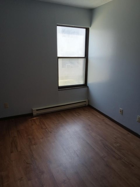 A room with a window and a wooden floor.
