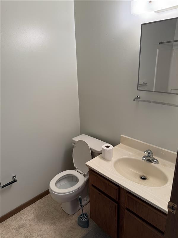 A white toilet with a roll of toilet paper on top of it is in a bathroom.
