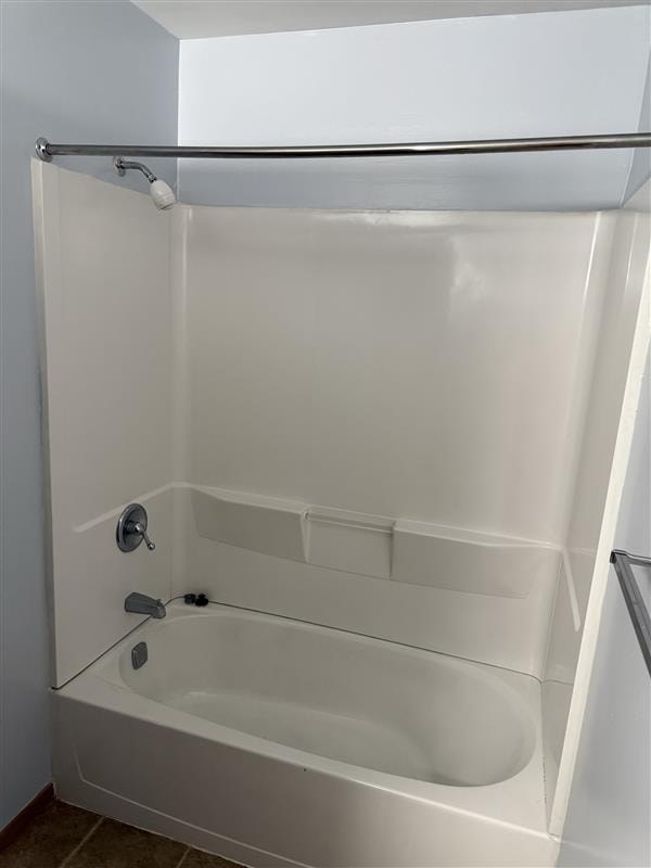 A white bathtub with a shower head and hand held shower.