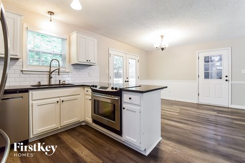 A kitchen with white cabinets and a black countertop.