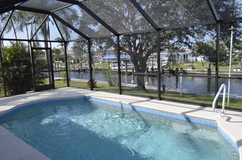 A pool with a glass enclosure and a waterfall.