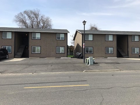 A parking lot in front of a building with a car parked in the lot.