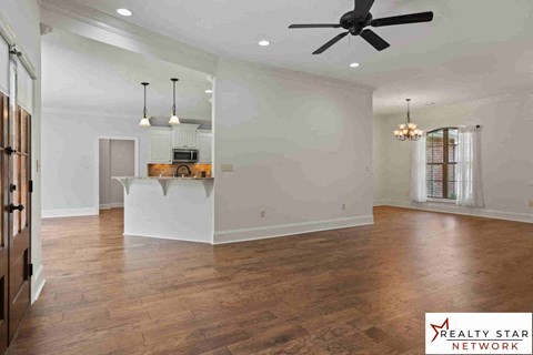 A spacious room with wooden floors and a ceiling fan.