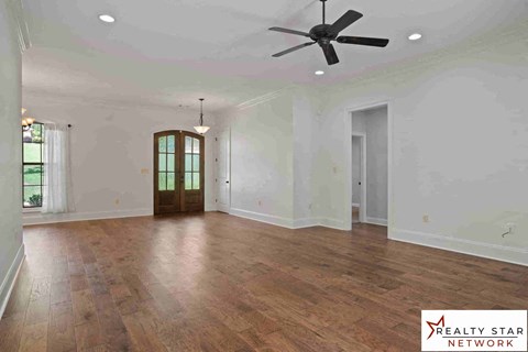 A spacious room with wooden flooring and a ceiling fan.