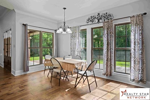 A dining room with a table set for four and a Realty Star Network logo.