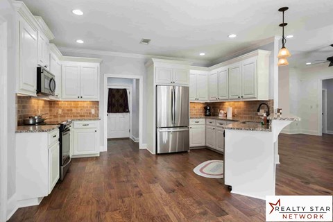 A kitchen with white cabinets and wooden floors.